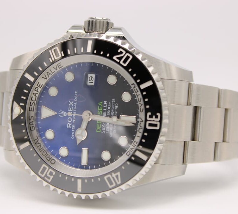 Close-up of a stainless steel Rolex Sea-Dweller diver's watch with a blue dial, black unidirectional bezel, and date window at 3 o'clock on a light background.]','Close-up of a Rolex Oyster Perpetual Date Sea-Dweller in stainless steel with blue gradient dial, bold hour markers, and a rotating bezel.
