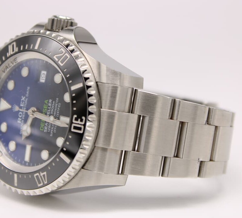 Stainless steel Rolex dive watch with a blue dial and black bezel resting on a white surface.